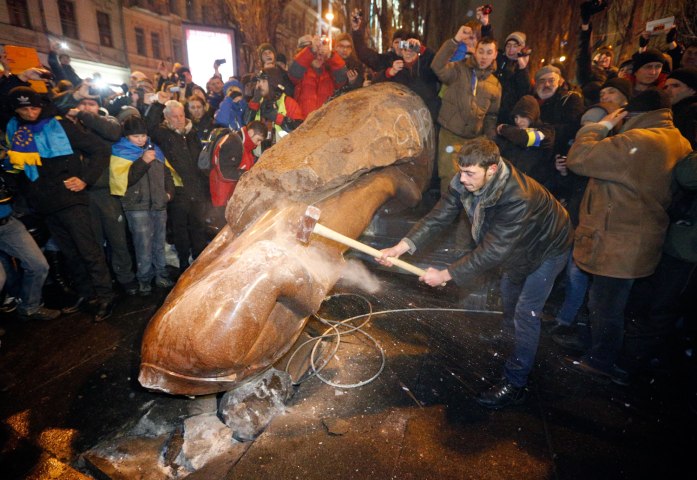 A protester hammers at a statue of former Soviet leader Vladimir Lenin after it was toppled during a pro-European protest in downtown Kiev, on Dec. 8, 2013. 