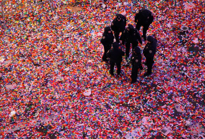 Police officers stand in confetti in Times Square shortly after midnight in New York City, on Jan. 1, 2014.