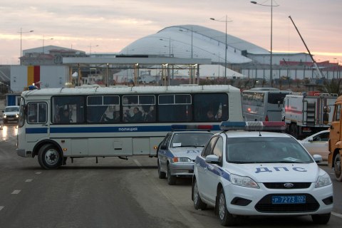 Russian police officers sit on a bus at an access road near venues at the Olympic Park near Sochi