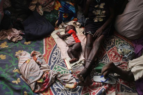 A baby sleeps next to a woman in a Catholic church in Malakal