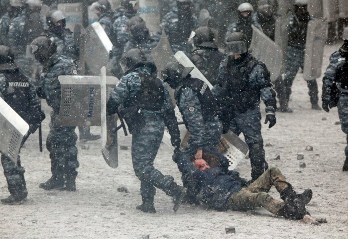Riot police officers hold a man during clashes with pro-European protesters in Kiev