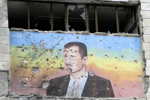 File photo of mural of Syria's President Assad riddled with holes on the facade of the police academy in Aleppo after it was captured by Free Syrian Army fighters