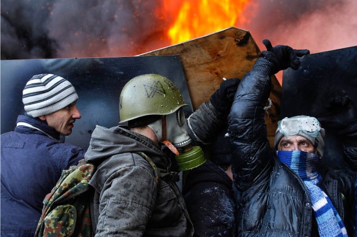 Pro-European integration protesters take cover from water sprayed from a fire engine at the site of clashes with riot police in Kiev