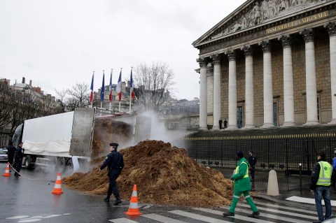 French police an municipal workers walk near a large pile of manure sits in front of the National Assembly in Paris