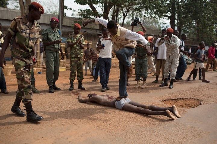 A man jumps on the corpse of a man, who was killed as he was accused of joining the ousted Seleka fighters, in Bangui