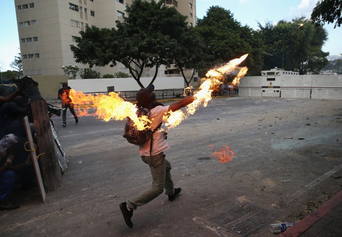 A protester hurls a molotov cocktail at national guard troops in one of the largest anti-government demonstrations yet on March 2, 2014 in Caracas.
