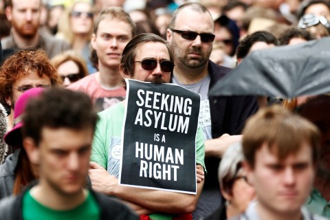 Man holds a poster during a raly in support of asylum seekers in central Sydney
