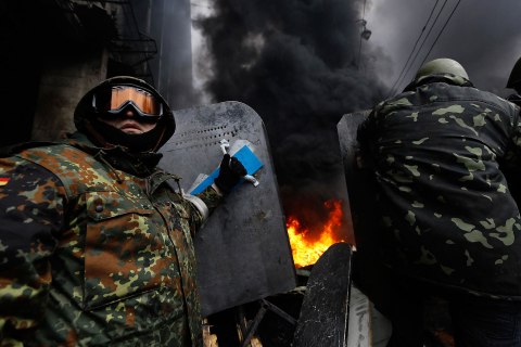 Anti-government protesters prepare to advance over a burning barricade in Kiev's Independence Square