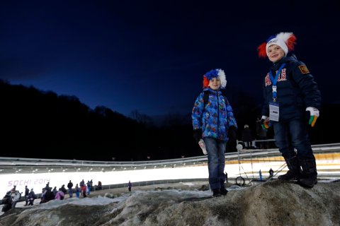 Children wait for the start of the final run during the men's doubles luge at the 2014 Winter Olympics, on Feb. 12, 2014, in Krasnaya Polyana, Russia.