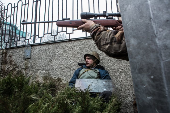An anti-government protester aims a gun in the direction of suspected sniper fire near the Hotel Ukraine on February 20, 2014 in Kiev.