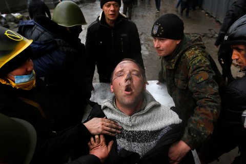 An injured man struggles to breathe as he is carried on a stretcher by anti-government protesters after clashes with riot police in the Independence Square in Kiev
