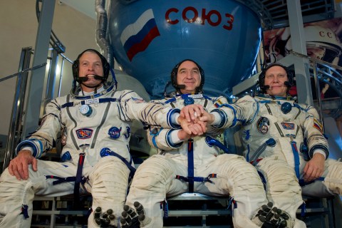 NASA astronaut Steven Swanson joins hands with Russian cosmonauts, Alexander Skvortsov and Oleg Artemyev in front of a mock-up of a Soyuz TMA spacecraft at the Gagarin Cosmonauts' Training Centre in Star City centre outside Moscow, on March 5, 2014. 